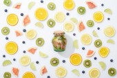 Detox-Drink im Glas zwischen aufgeschnittenen Früchten und Blaubeeren auf weißem Hintergrund