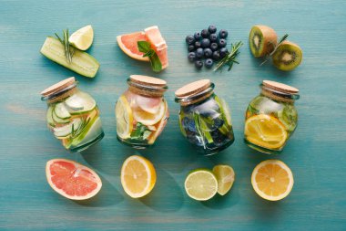 top view of detox drinks in jars with citrus fruits, berries and cucumbers clipart