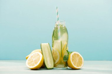 Detoks İçecek şişe yakın limon, nane ve salatalık mavi üzerinde izole