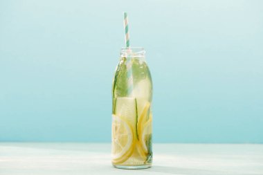 mavi üzerinde izole saman, limon, nane ve salatalık ile şişe Detox içecek