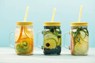 mavi üzerinde izole Pipetler ile meyveler, meyveler ve otlar ile organik Detox İçecekler 