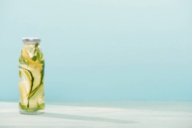 limon ile şişe Detox içecek, mavi üzerinde izole salatalık
