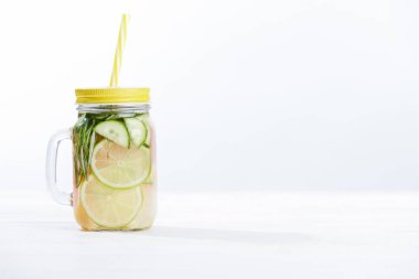 Beyaz arka planda Limes, salatalık, biberiye ve greyfurt ile kavanozda taze Detox içecek