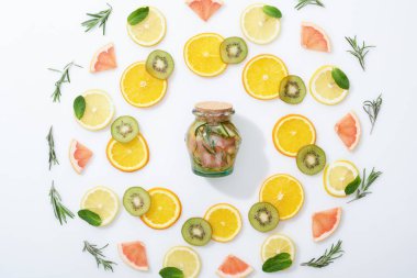 düz dilimlenmiş kivi ile yatıyordu, portakal, limon, greyfurt, nane, biberiye ve gri arka planda kavanoz içinde taze Detox içecek