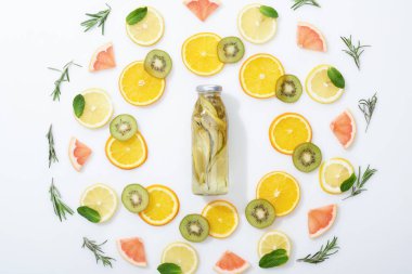 gri arka planda dilimlenmiş kivi, portakal, limon, greyfurt, nane, biberiye ve Detox içeceği ile düz yatıyordu