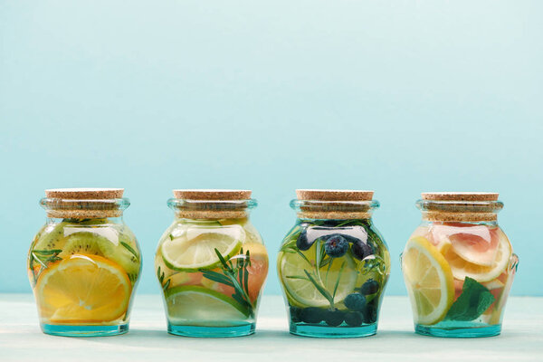 fresh detox drinks in jars with fruits and herbs isolated on blue