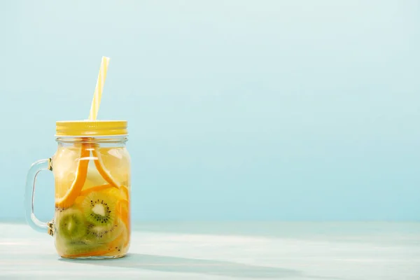 用橘子 猕猴桃和秸秆在蓝色上隔离的罐装排毒饮料 — 图库照片