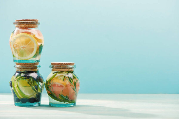 detox drinks in jars with fresh fruits isolated on blue