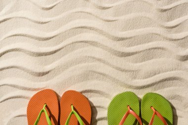 kopya alanı ile dalgalı kum üzerinde renkli Flip flop üst görünümü