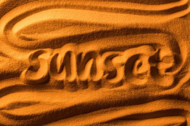 top view of word sunset written in sand with smooth waves and color filter clipart