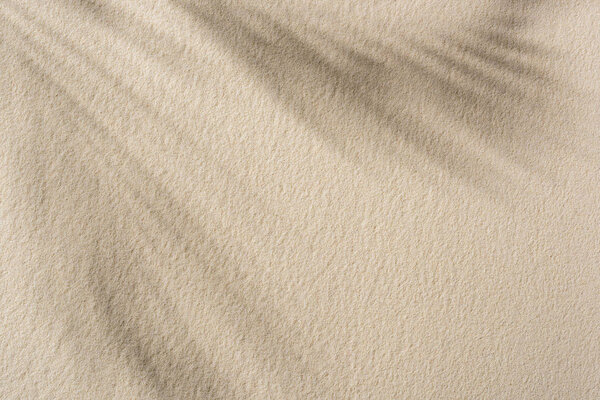 top view of beige sandy background with shadow and copy space