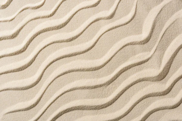 滑らかな波とベージュの砂浜の背景のトップビュー — ストック写真