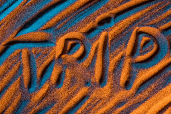 top view of word trip written in sand with smooth waves and color filter