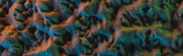 panoramic shot of textured sand with orange, green and blue lights