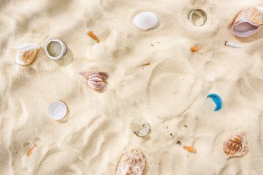 deniz kabukları üst görünümü, şişe kapakları, dağınık sigara izmaritleri, kum plastik şişe kapakları
