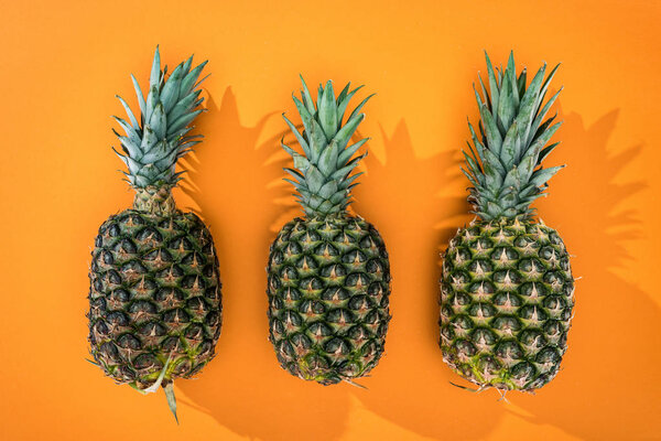top view of pineapples with side shadows on orange background