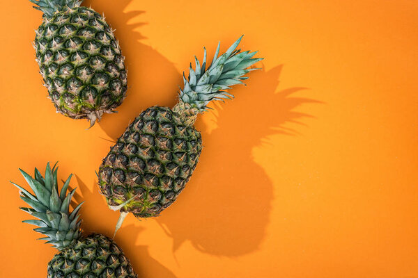 top view pineapples with shadows an on orange background and copy space