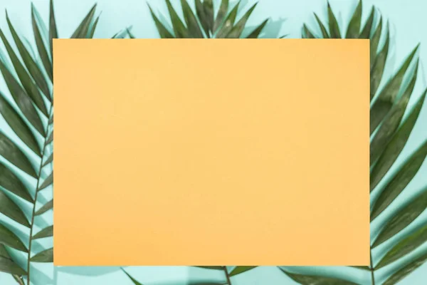 热带叶子和绿松石背景上的空橙色卡片的顶视图 — 图库照片