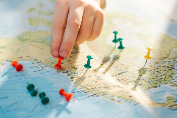 Cropped view of man with colorful push pins on world map
