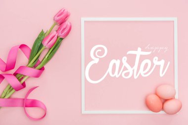 pembe arka plan üzerinde mutlu Paskalya yazı ile çerçeve yakınında kurdele ve boyalı yumurta ile pembe lale buketüst görünümü