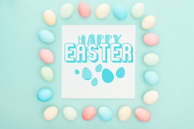 beyaz tebrik kartı mavi mutlu Paskalya yazı ile mavi arka plan boyalı tavuk yumurtası yapılmış kare kare üst görünümü