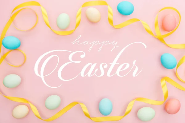 粉红背景上涂有五颜六色的鸡蛋和缎带的顶视图 带有快乐的复活节字母 — 图库照片