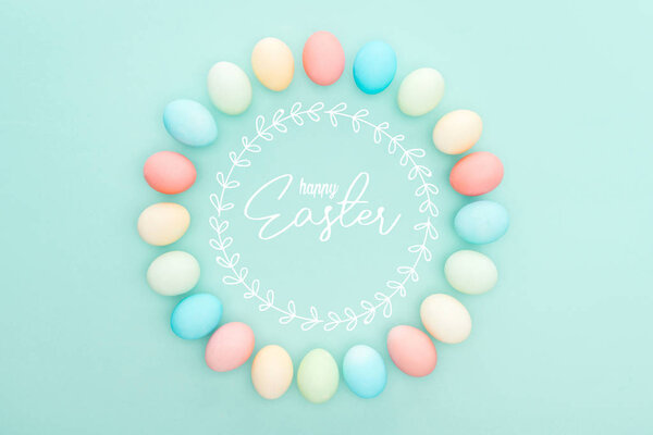 top view of round frame made of painted chicken eggs on blue background with happy Easter lettering 