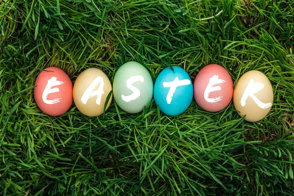 Vista Superior Huevos Multicolores Pintados Con Palabra Pascua Sobre Hierba — Foto de Stock
