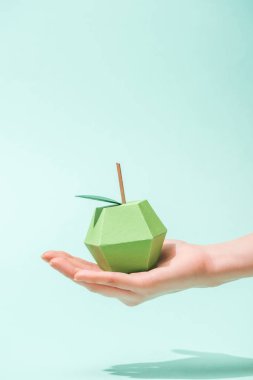 cropped view of young woman holding handmade paper apple on turquoise with copy space clipart