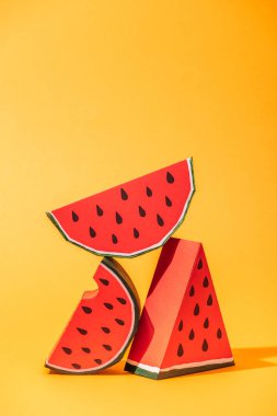 red paper watermelon slices on orange with copy space clipart
