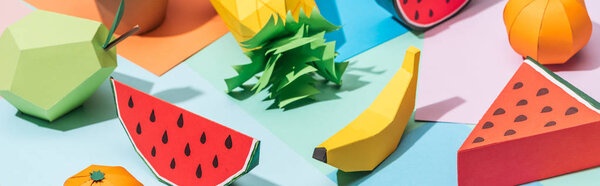 panoramic shot of handmade cardboard fruits on multicolored paper