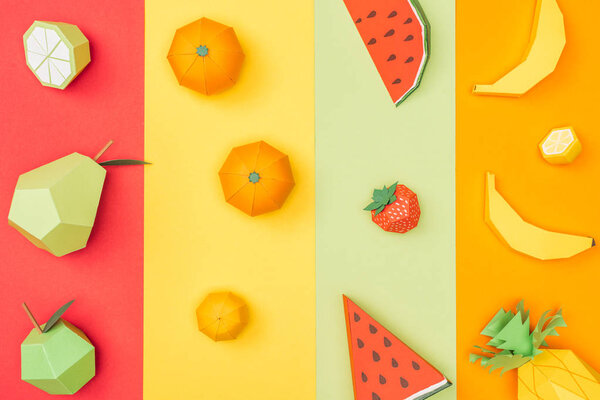 top view of various handmade origami fruits on multicolored paper stripes
