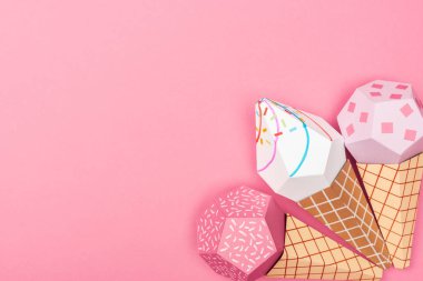 top view of handmade colorful origami ice cream cones isolated on pink with copy space clipart