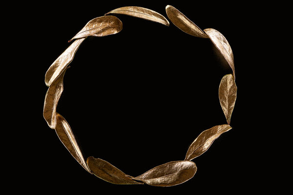 top view of circle made of golden metal decorative leaves isolated on black with copy space