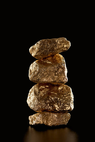 stack of gold textured shiny stones isolated on black