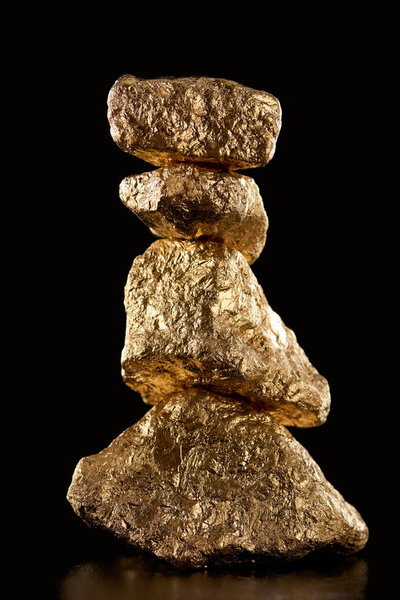 four gold textured shiny stones isolated on black 