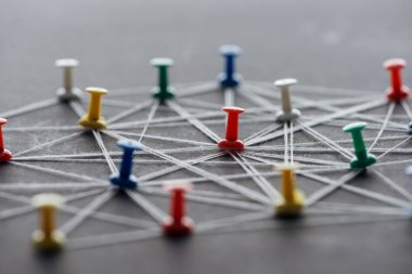 selective focus of colorful push pins connected with strings on grey, network concept clipart