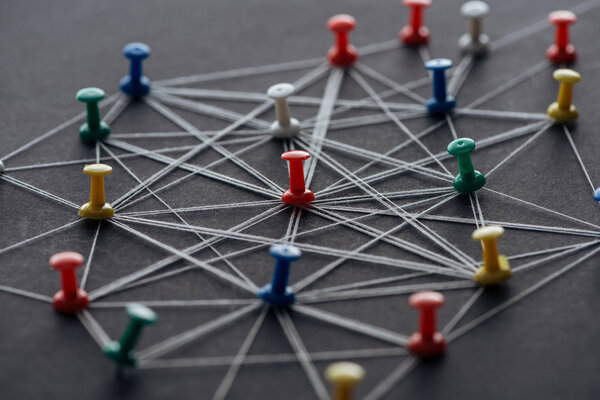 selective focus of push pins connected with strings isolated on grey, network concept
