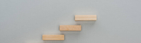 panoramic shot of wooden bricks symbolizing career ladder isolated on grey