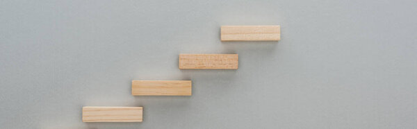 panoramic shot of wooden blocks symbolizing career ladder isolated on grey