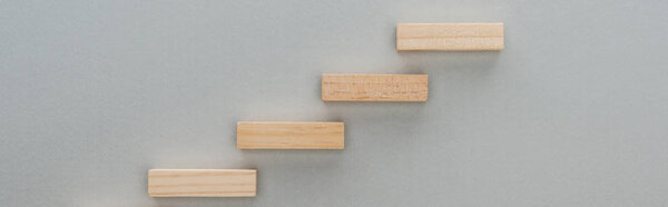 panoramic shot of wooden blocks symbolizing career ladder isolated on grey