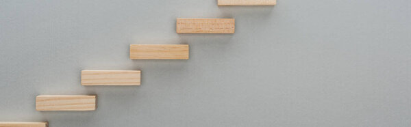 panoramic shot of wooden blocks symbolizing career ladder isolated on grey with copy space