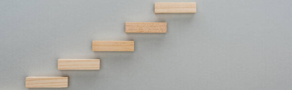 panoramic shot of wooden blocks symbolizing career ladder isolated on grey with copy space