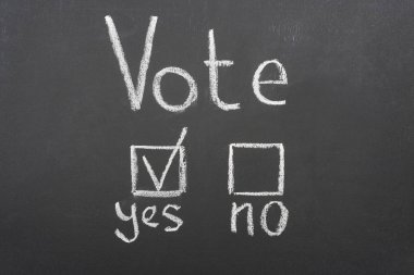 top view of white vote lettering and check mark near yes word on black chalkboard clipart