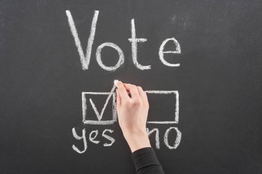 top view of voter putting check mark near yes word on black chalkboard clipart