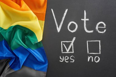 lgbt bayrağı yakınındaki siyah tebeşir tahtasında evet kelimesine yakın oy yazıve onay işareti üst görünümü