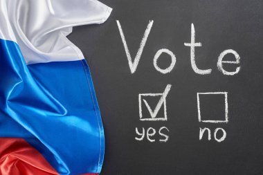 top view of vote lettering and check mark near yes word on black chalkboard near flag of Russia clipart