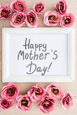 mutlu anneler gün yazı ve ahşap masa üzerinde pembe eustoma çiçekleri ile çerçeve üst görünümü
