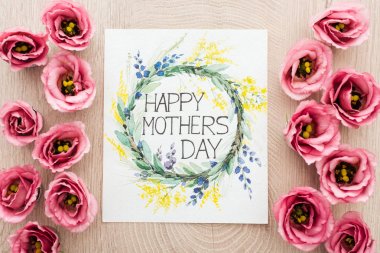 ahşap yüzeye yazılı mutlu anneler günü ile eustoma çiçek ve kart üst görünümü