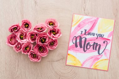 eustoma çiçek ve kart yapılmış kalp işareti üst görünümü i ahşap yüzeye anne yazı seviyorum